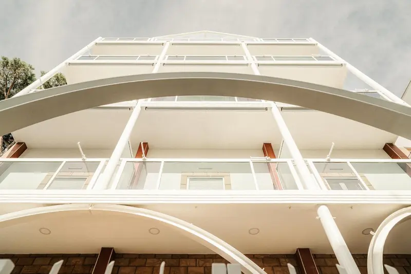 Façade d'un bâtiment blanc à plusieurs étages avec des balcons.