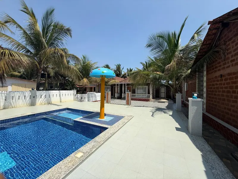 Une piscine rectangulaire bordée d'une terrasse carrelée, avec des palmiers en arrière-plan.
