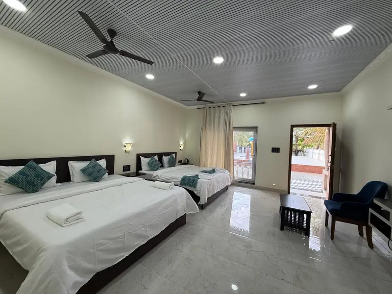 Chambre lumineuse avec deux lits et accès à une terrasse.