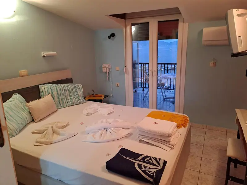 Une chambre lumineuse avec un lit fait et un accès à une terrasse.
