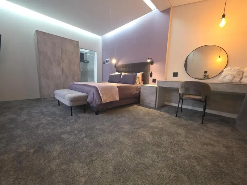 Une chambre moderne avec un grand lit et un coin coiffeuse.