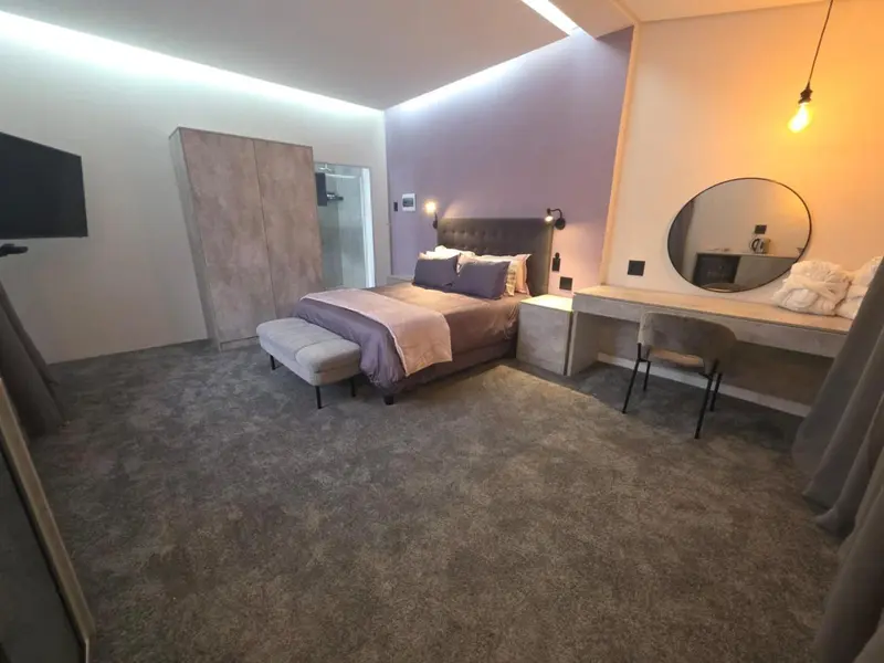 Une chambre moderne avec un grand lit et un espace coiffeuse.