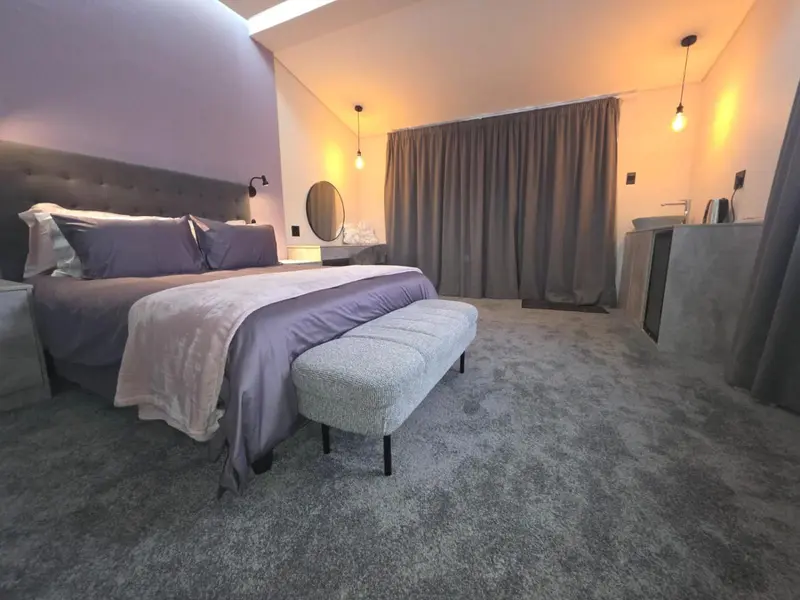 Une chambre moderne avec un grand lit et un éclairage tamisé.