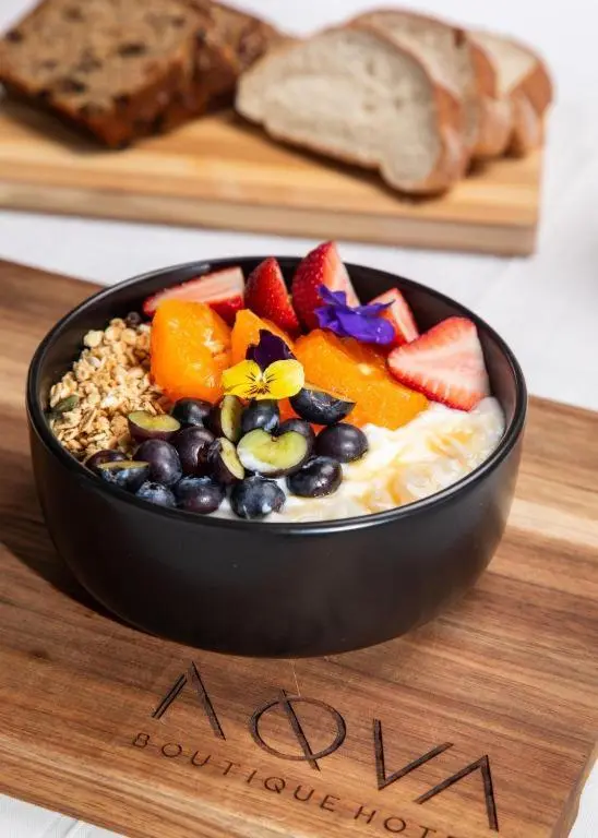 Un bol de smoothie aux fruits frais et aux céréales est présenté sur une planche en bois.