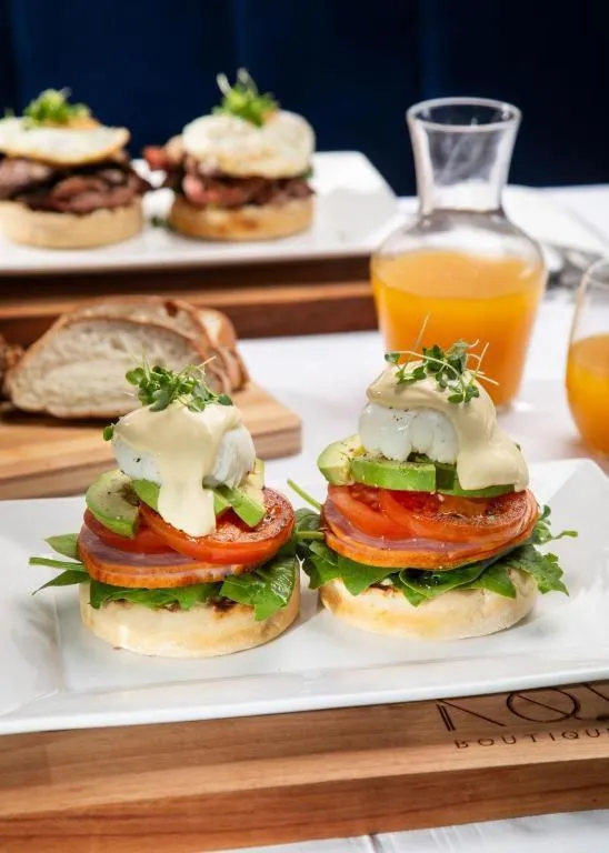 Assiettes de brunch avec œufs pochés, avocat et pain, accompagnées de jus d'orange.