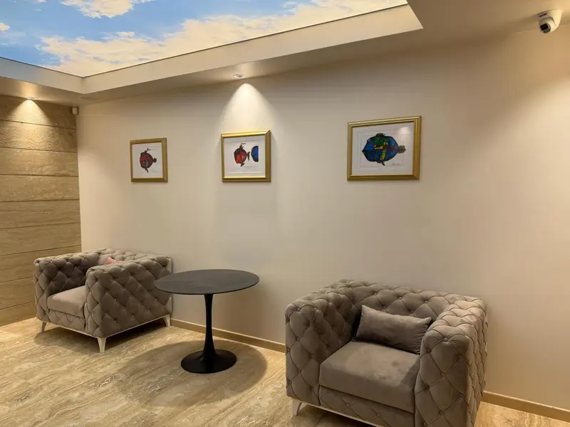 Un espace de détente avec des fauteuils et une table basse devant un mur décoré.