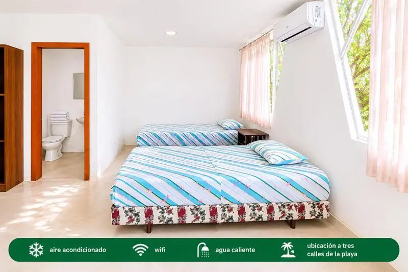 Une chambre lumineuse avec deux lits simples et une salle de bain attenante.