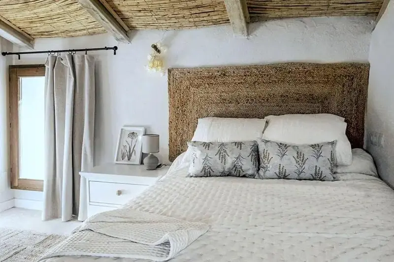 Une chambre lumineuse avec un lit recouvert de coussins et d'une couverture.
