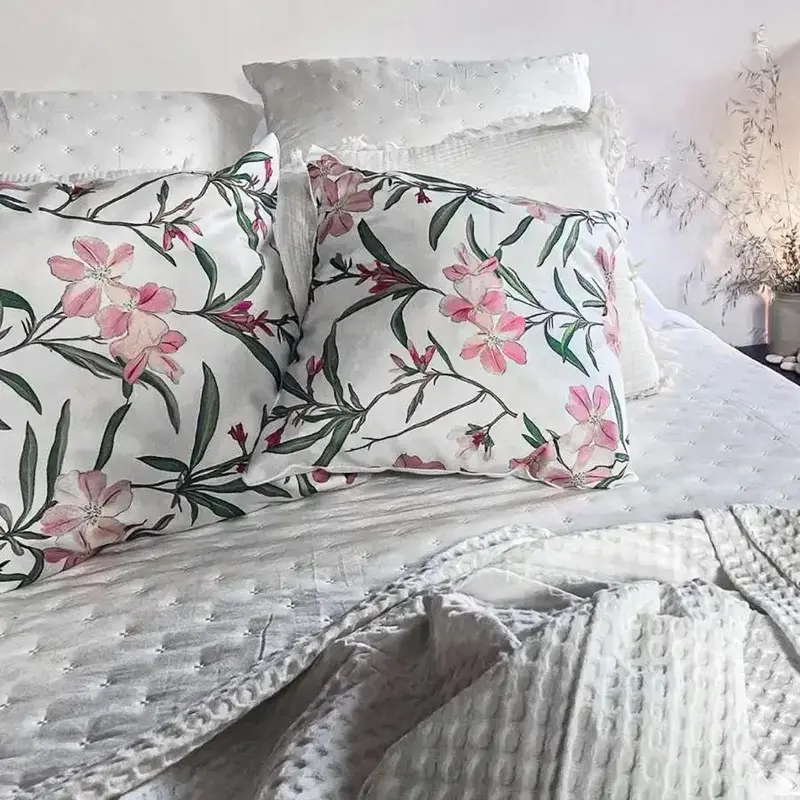 Coussins fleuris sur un lit blanc.