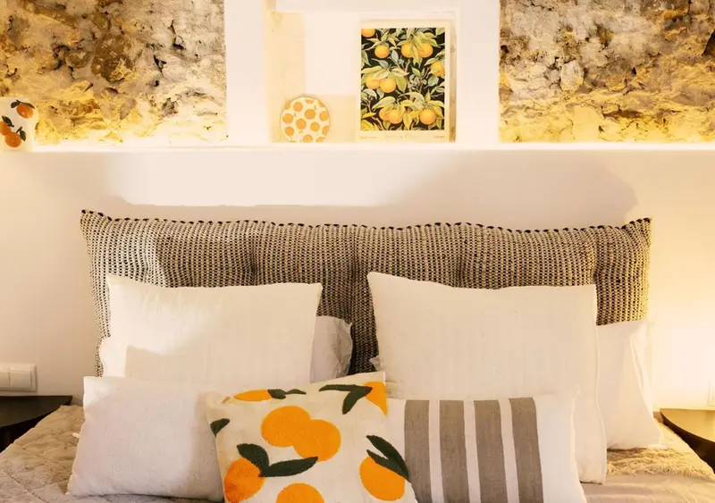 Un lit double avec une tête de lit texturée et des coussins décoratifs.