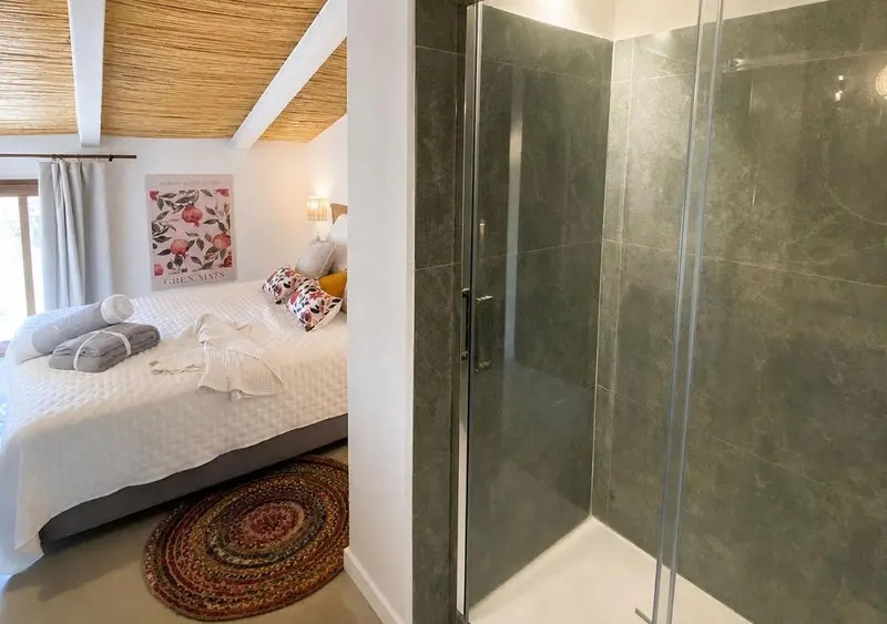 Une chambre lumineuse avec un lit et une douche à l'italienne.