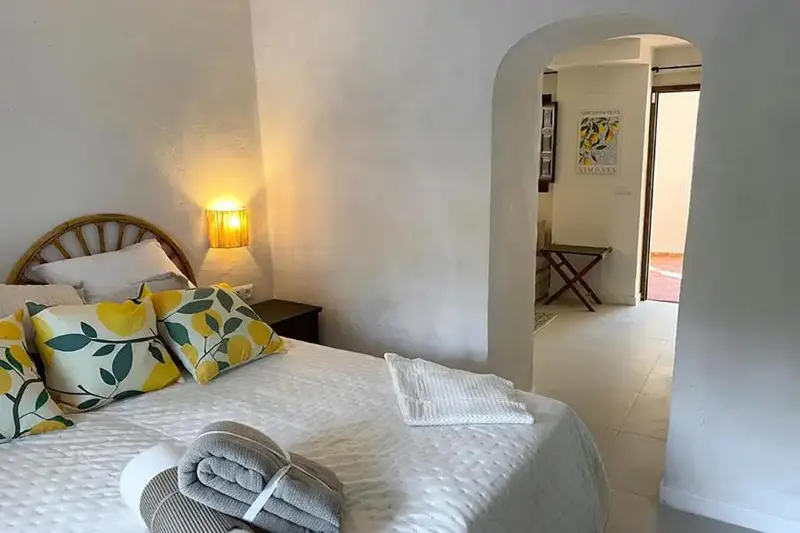 Une chambre lumineuse avec un lit recouvert d'oreillers et de coussins.