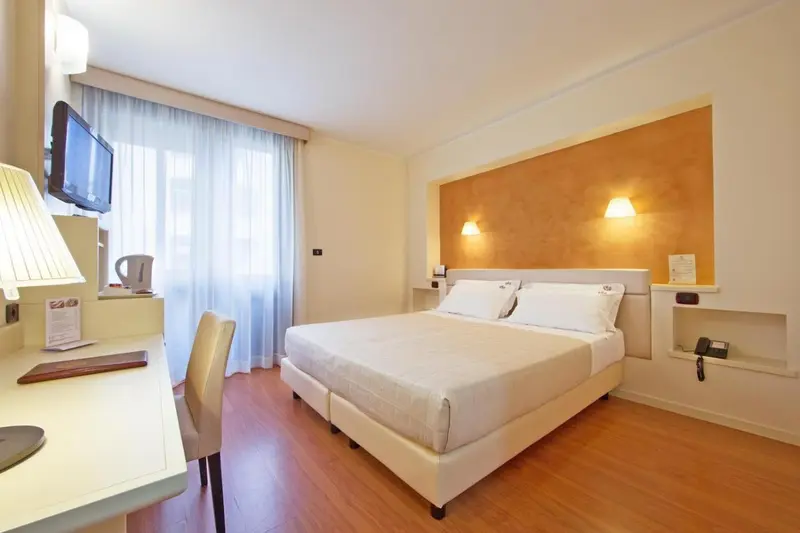 Une chambre lumineuse avec un grand lit et un bureau.