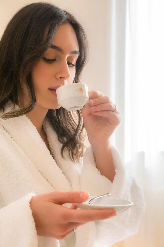 Une femme savoure une boisson chaude dans un intérieur clair.