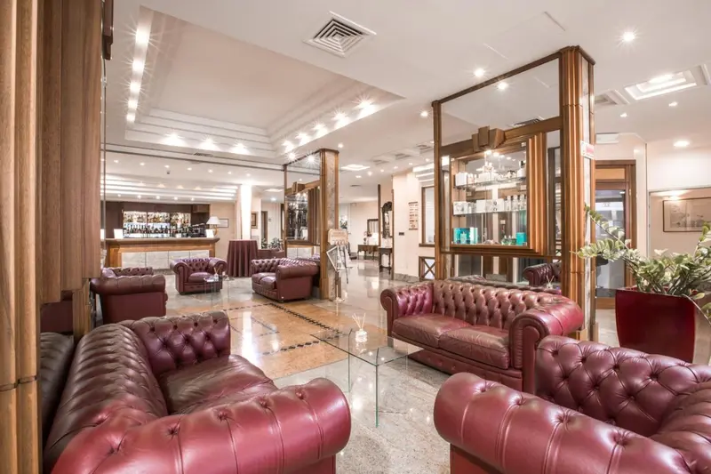 Un espace de détente avec des canapés en cuir rouge et un comptoir de bar en fond.