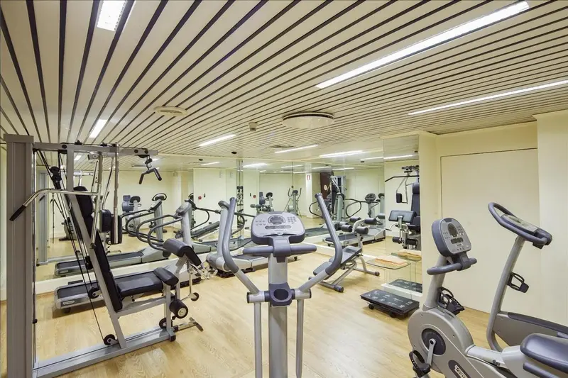 Une salle de sport lumineuse avec plusieurs appareils de fitness et des miroirs.