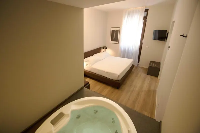 Une chambre lumineuse avec un lit double et un jacuzzi.