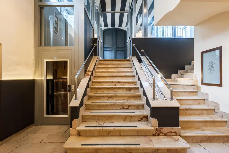 Escalier en marbre beige dans un hall d'entrée lumineux.