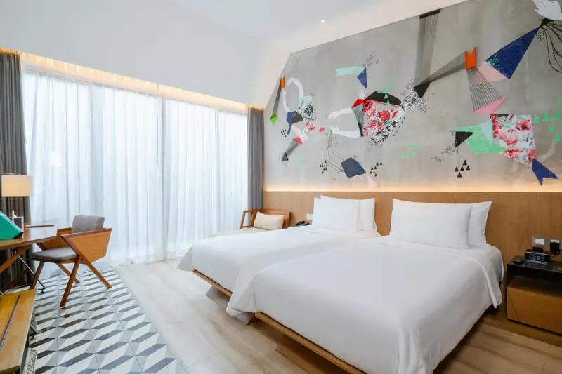 Chambre lumineuse avec un grand lit et un mur décoratif.