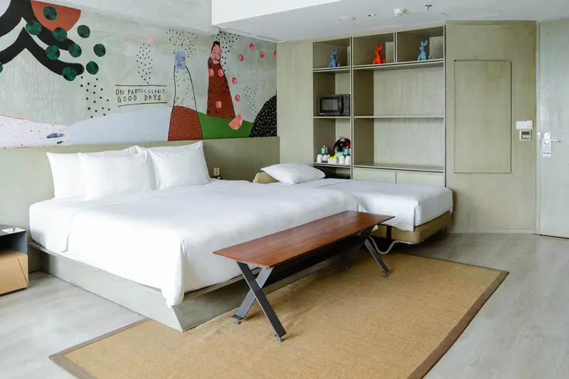 Une chambre lumineuse avec un grand lit et une décoration murale colorée.