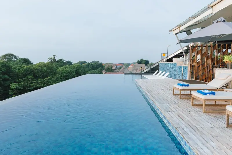 Une piscine à débordement offre une vue sur la végétation luxuriante.
