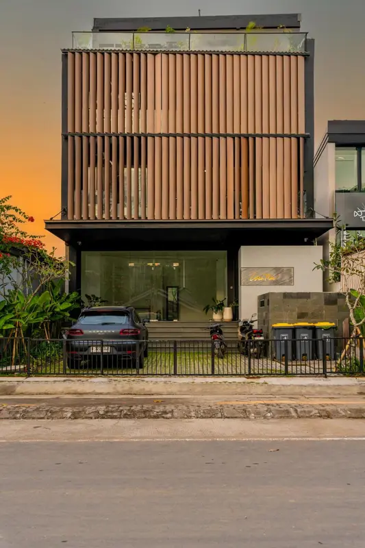 Facade moderne d'un bâtiment avec un garage et une végétation tropicale.