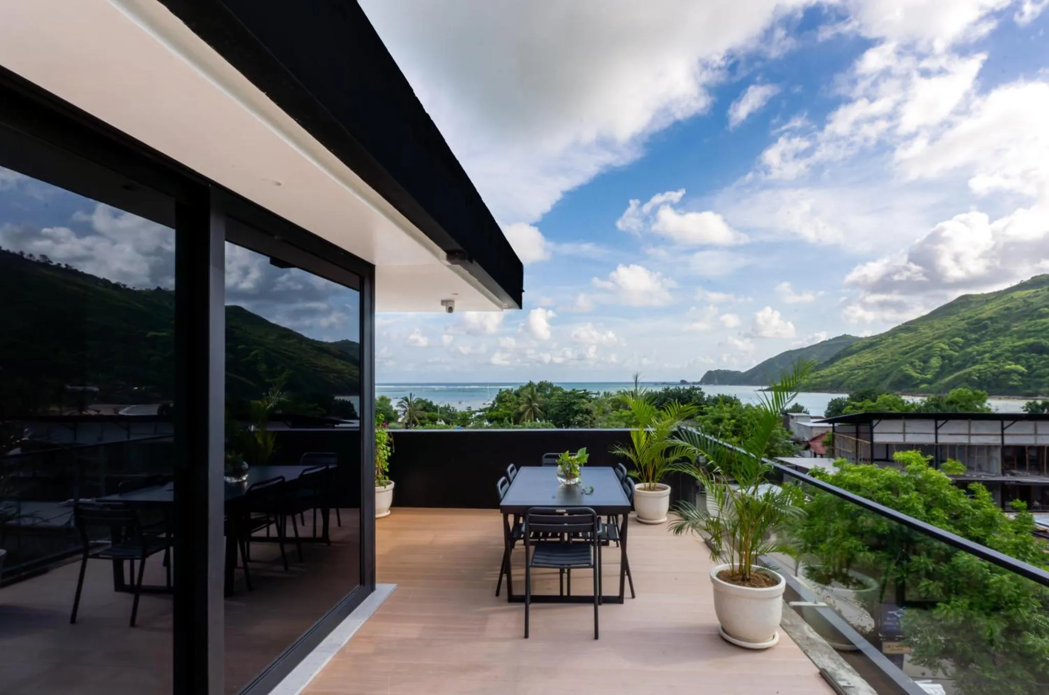 Terrasse avec mobilier et vue sur la mer et les collines.