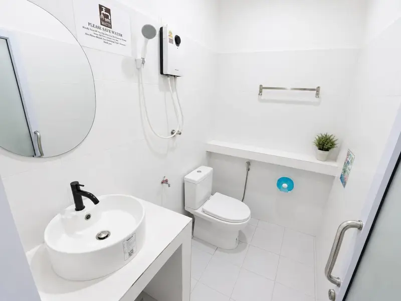 Une salle de bain claire avec douche, lavabo et toilettes.