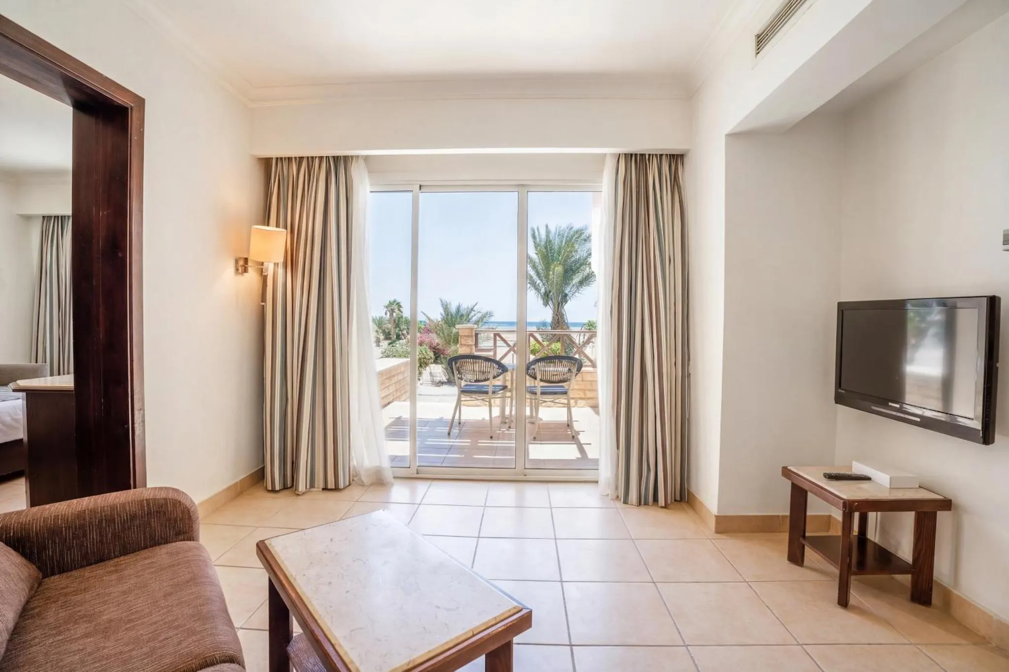 Espace de séjour lumineux avec canapé et accès à une terrasse offrant une vue sur la mer.
