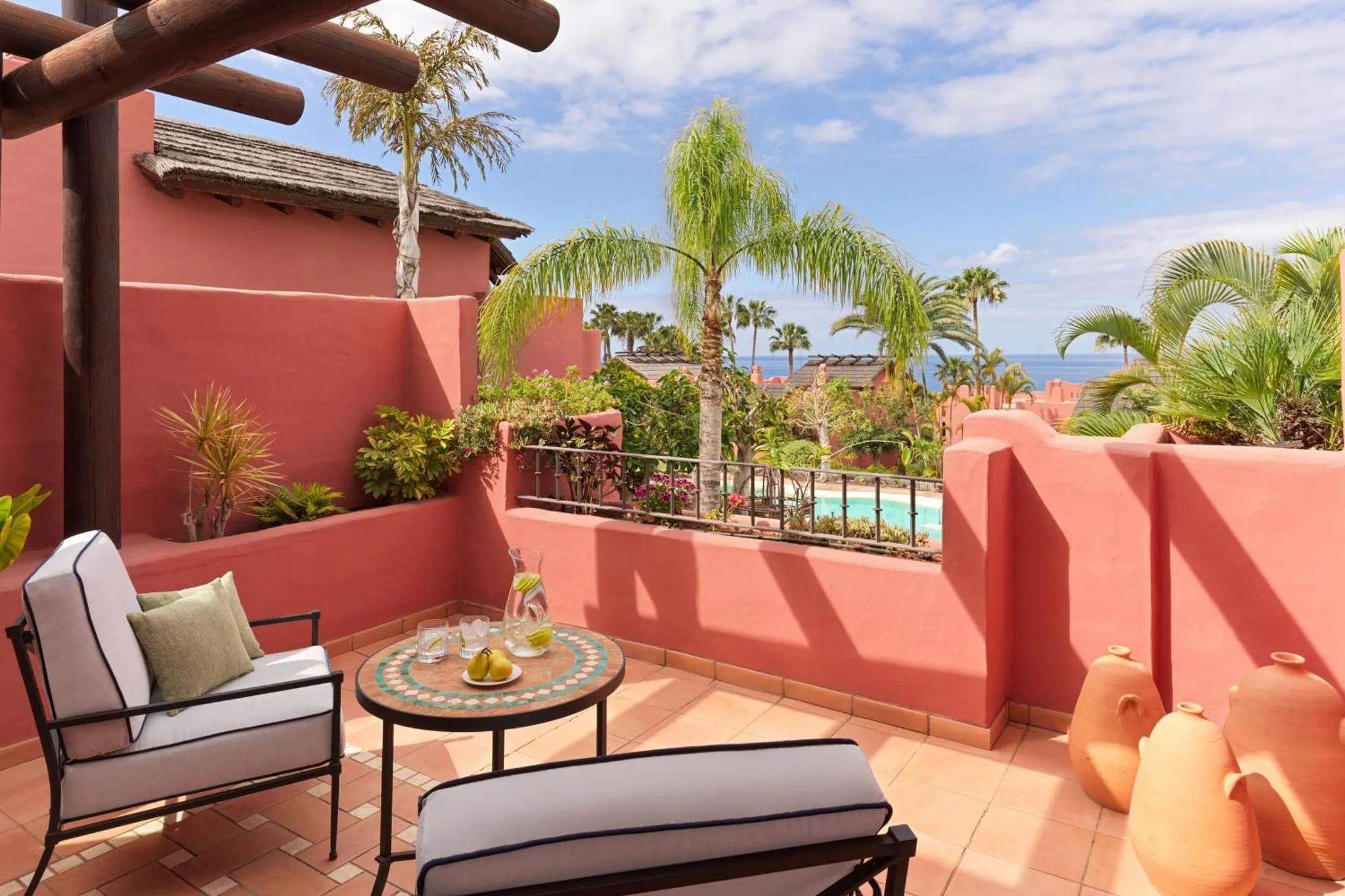 Terrasse ombragée avec mobilier d'extérieur et vue sur la mer.