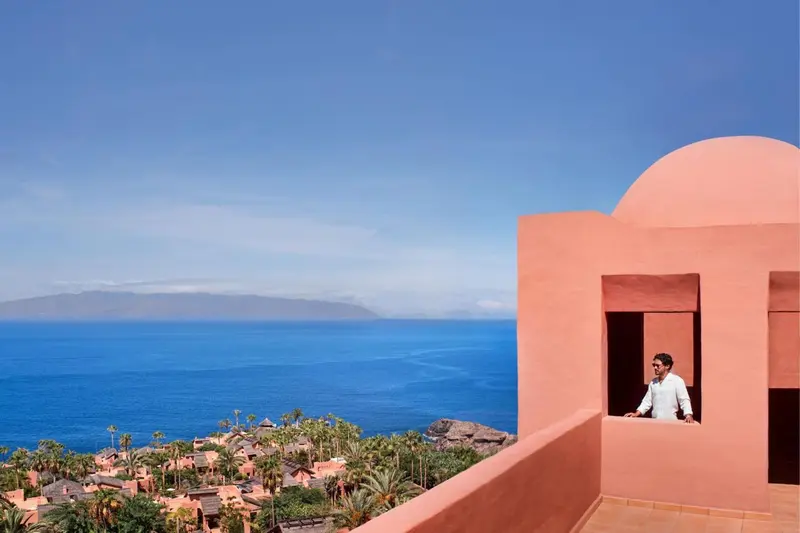 Vue d'une terrasse avec une architecture colorée et une vue sur la mer.