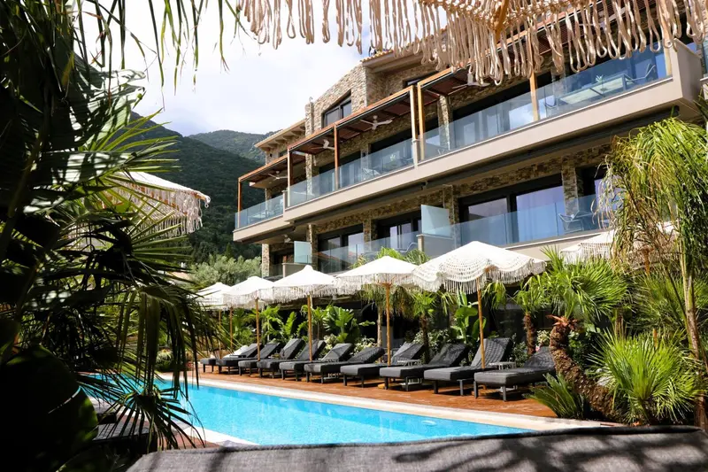 Bâtiment à plusieurs étages avec des balcons et des transats au bord d'une piscine.