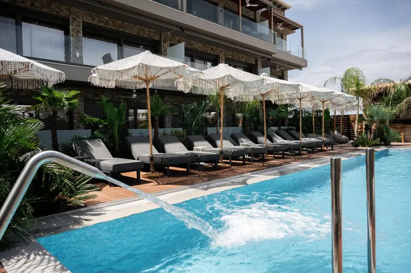 Transats et parasols bordent une piscine turquoise.