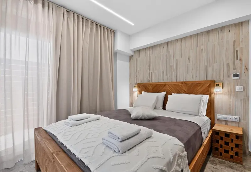 Une chambre lumineuse avec un grand lit et des rideaux clairs.