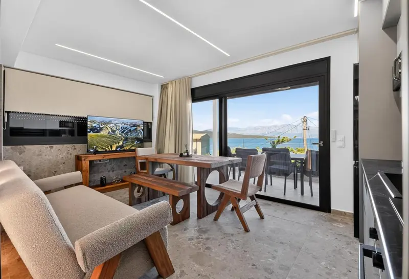 Espace de vie lumineux avec canapé, table et accès à une terrasse vue sur mer.