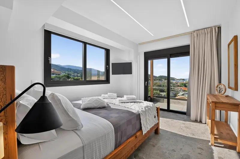 Une chambre lumineuse avec un lit double et une vue sur un paysage montagneux.