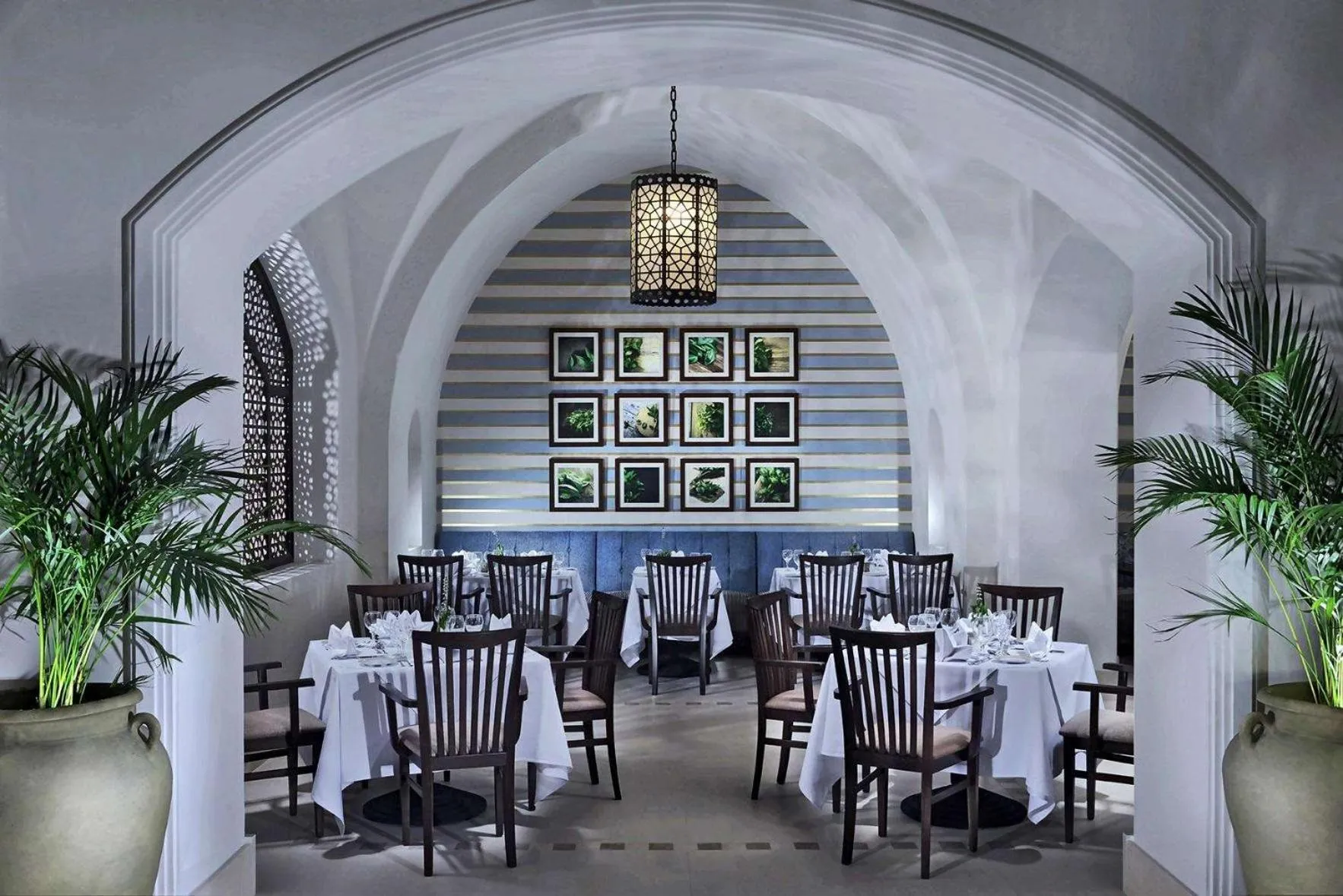 Une salle à manger lumineuse avec des tables dressées et une décoration murale rayée.