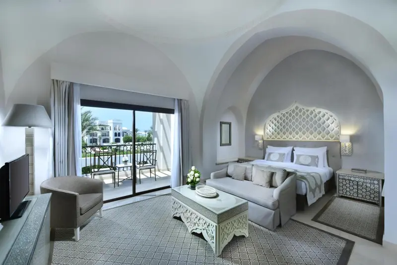 Une chambre lumineuse avec un canapé et un accès à un balcon.