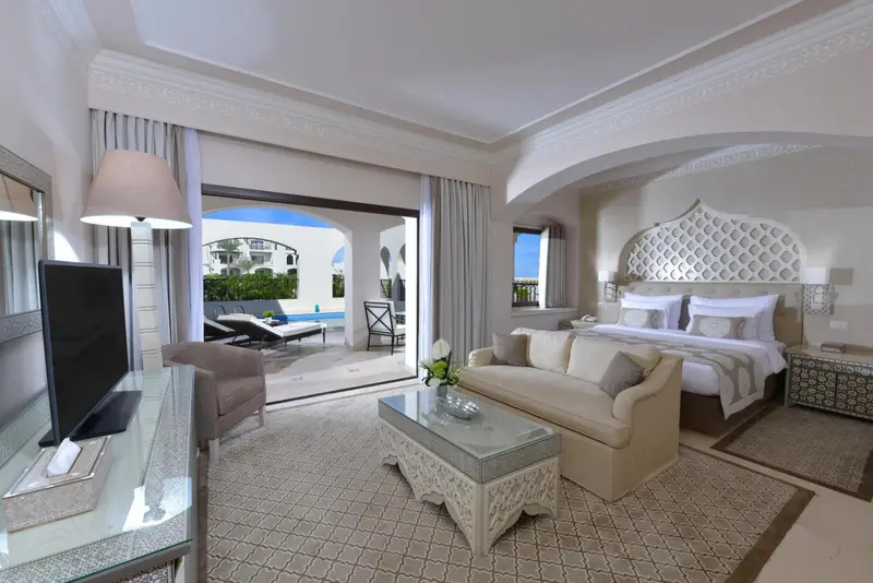 Chambre lumineuse avec canapé et accès à une terrasse privée avec piscine.