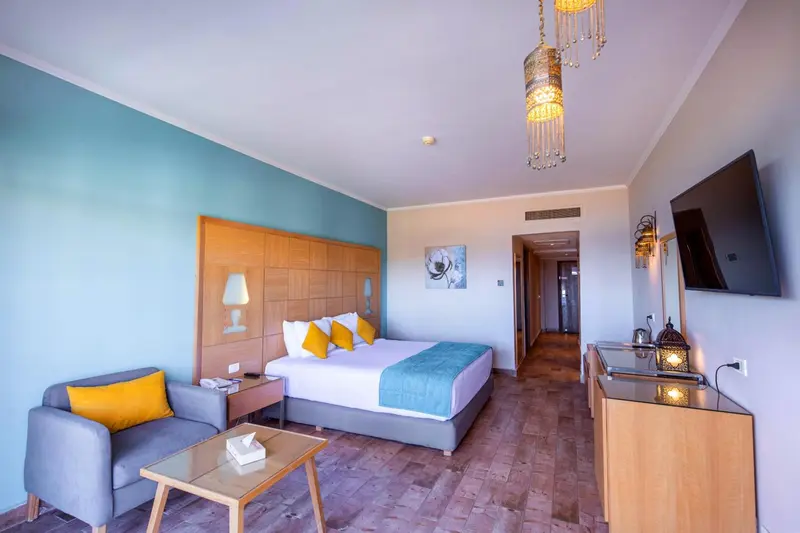 Une chambre lumineuse avec un lit double et un coin salon.