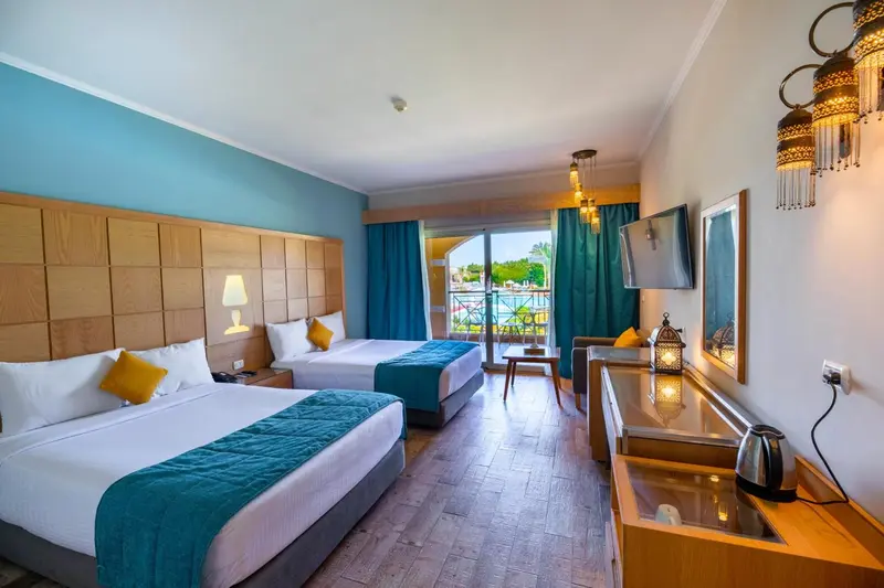 Chambre lumineuse avec deux lits simples et une vue sur la mer.