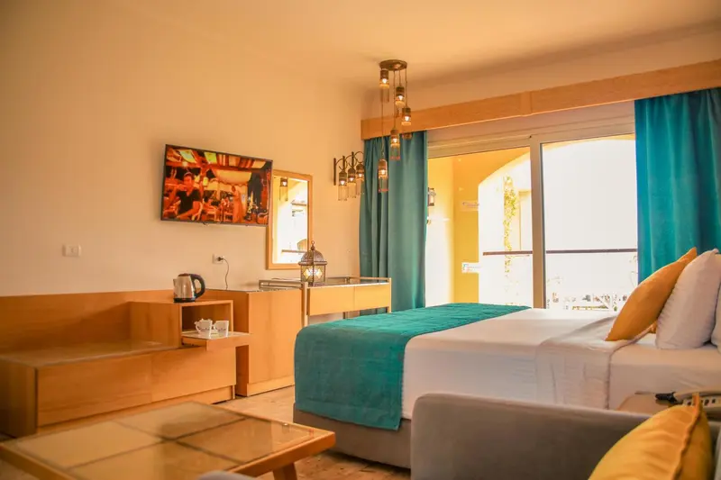 Chambre lumineuse avec un lit fait et un canapé près d'une baie vitrée.