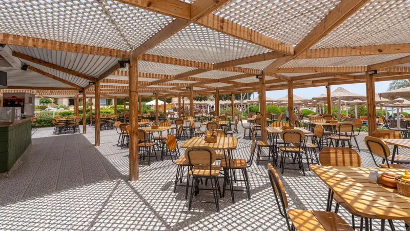 Terrasse ombragée avec tables et chaises en bois.