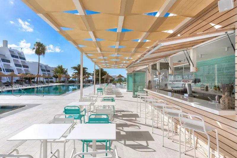 Terrasse ombragée avec tables et chaises près d'un bar.
