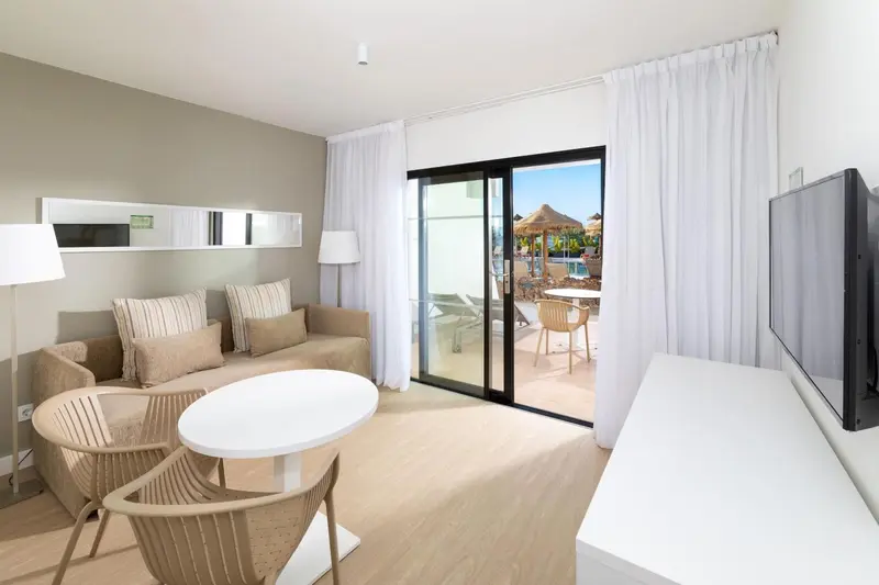 Espace de vie lumineux avec canapé, table basse et accès à une terrasse.