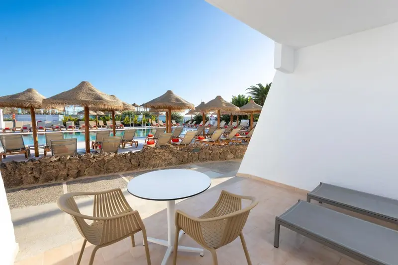 Terrasse avec mobilier d'extérieur donnant sur une piscine ensoleillée.
