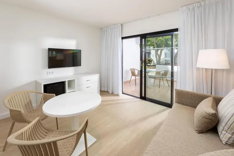 Espace de vie lumineux avec canapé, table et accès à une terrasse.