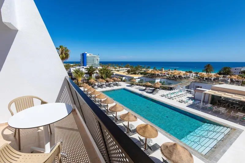 Vue d'une piscine depuis un balcon avec mobilier d'extérieur.