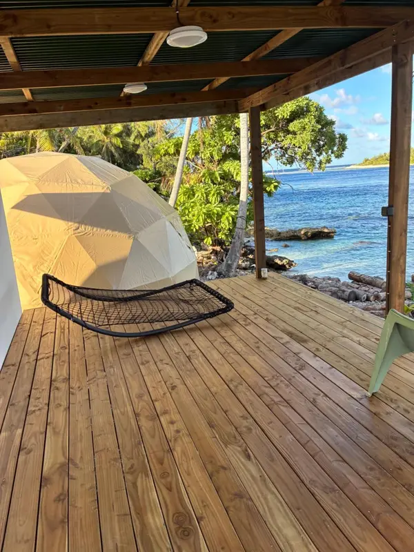 Terrasse en bois avec hamac donnant sur la mer.