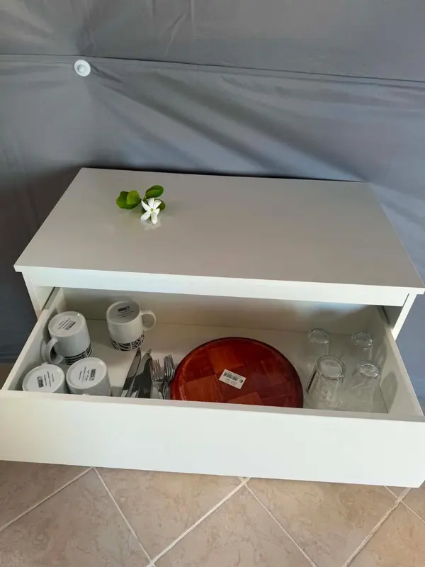 Vaisselle et couverts rangés dans un meuble bas.